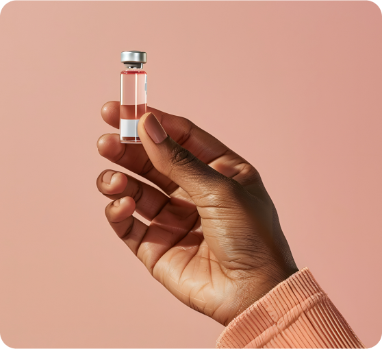A hand holding a small glass vial filled with pink liquid